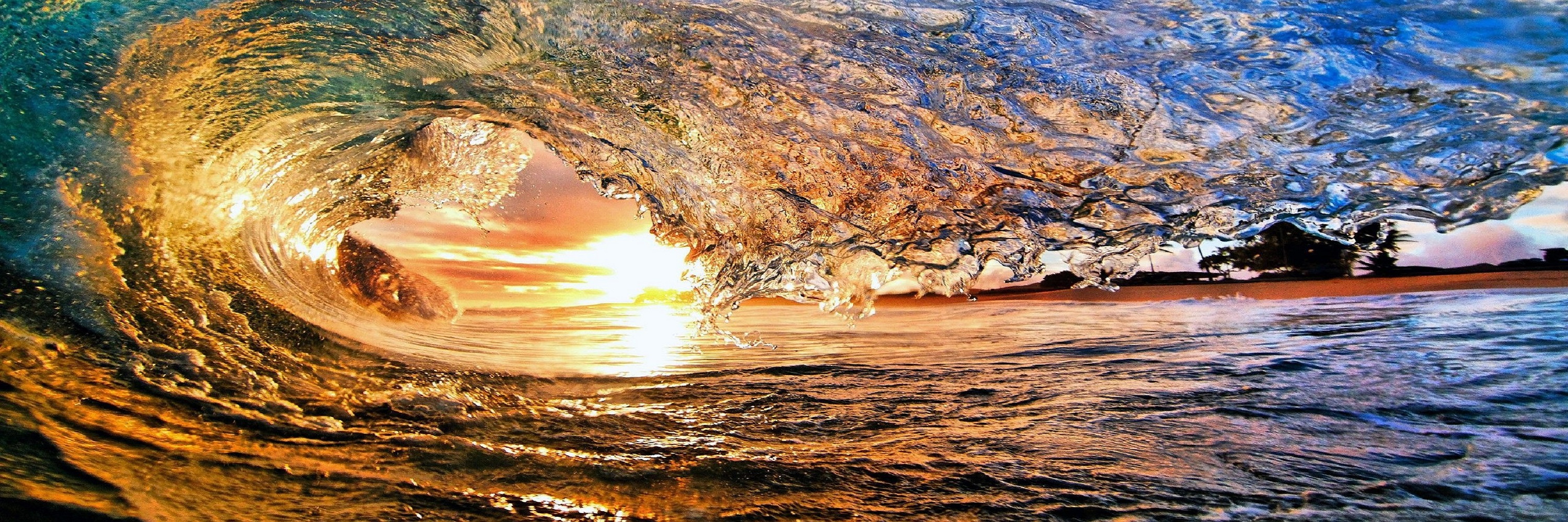 Close up picture of a wave with a sunset behind it.